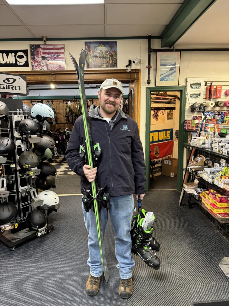 man holding a new pair of skis bought at burrows sports in brattleboro